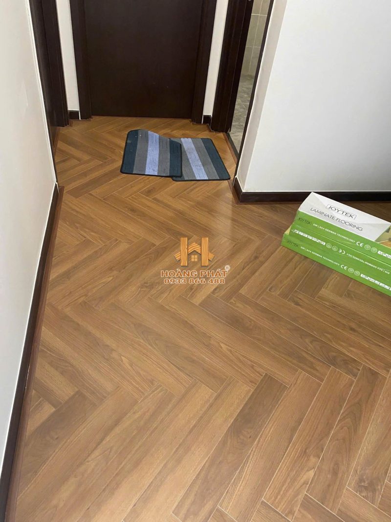 Không gian lát sàn JoyTek xương cá HR05 với tường trắng và cửa gỗ tối màu